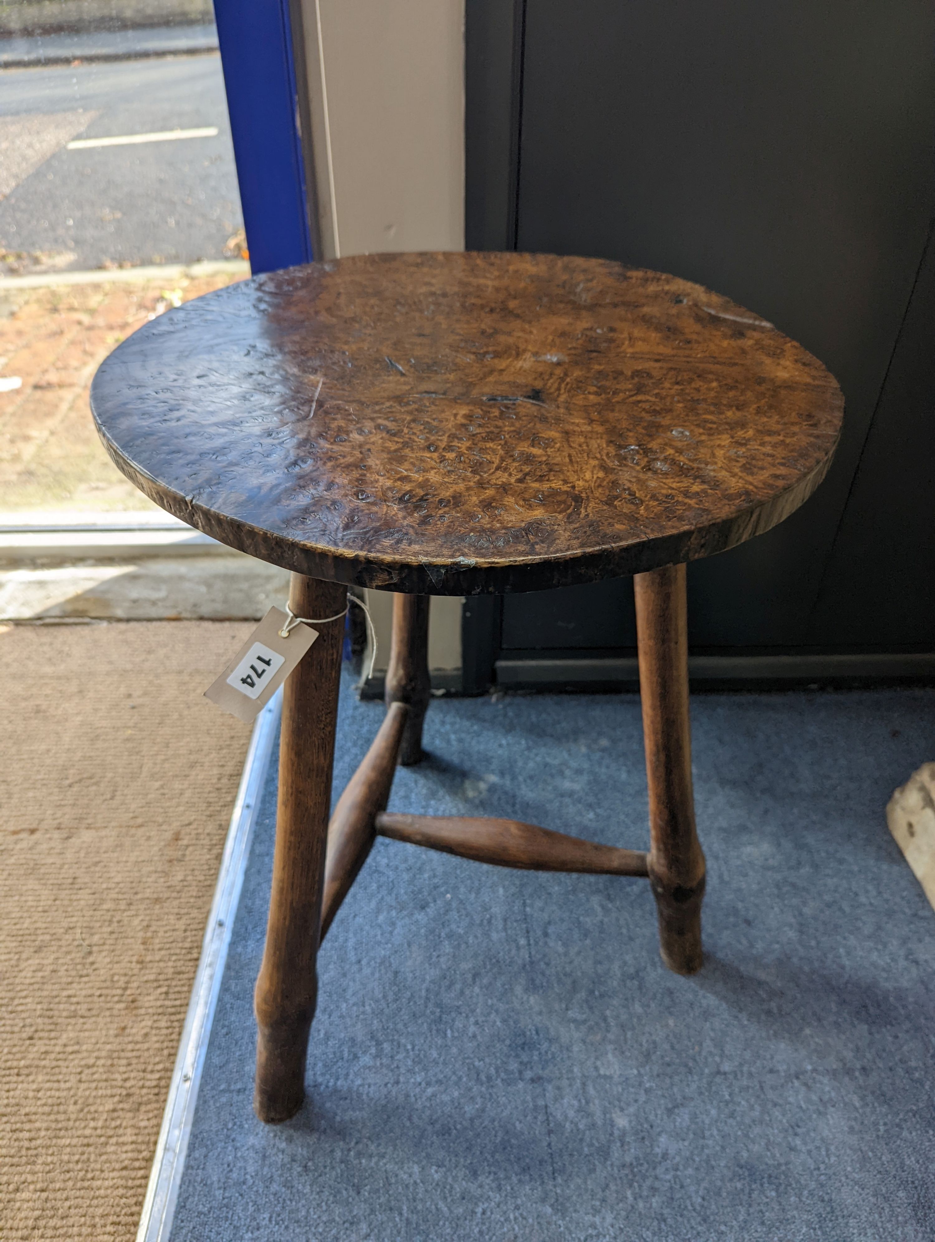 A circular burr elm and ash primitive cricket table with T shaped stretcher, diameter 44cm, height 61cm